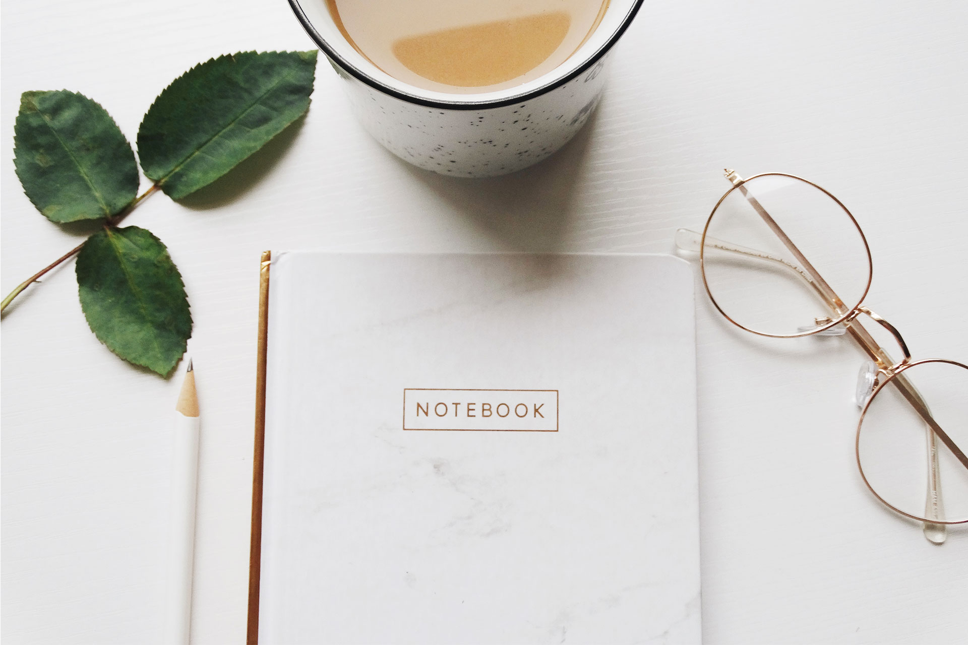 An inviting image showcasing a well-organized study corner with a cup of aromatic coffee, a notebook ready for ideas, and a pair of glasses resting on a clean white desk.